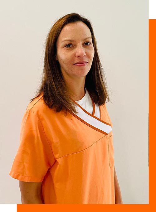 Eine Frau in orangefarbener Kleidung lächelt leicht vor einem weißen Hintergrund.
