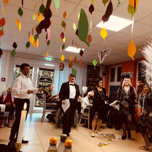 Menschen in festlicher Kleidung und Kostümen feiern lachend unter bunten Blättern