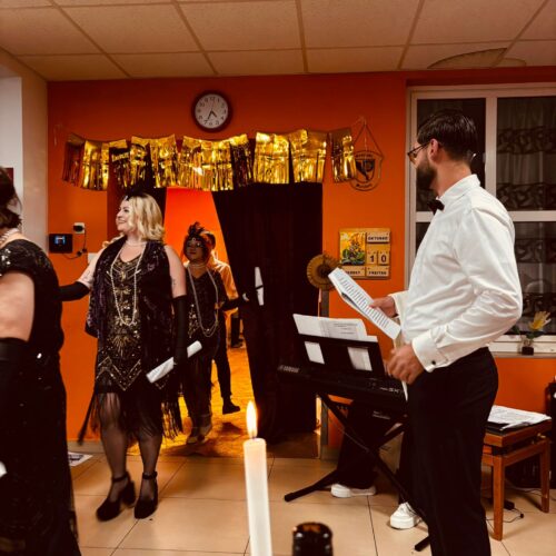 Mehrere elegant gekleidete Erwachsene bei einer Feier mit goldener Deko und Kerzenlicht