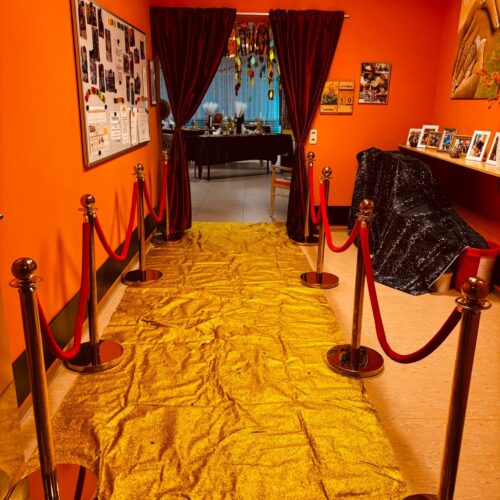 Ein mit goldenem Stoff ausgelegter Flur mit rotem Vorhang und dekorativen Bildern