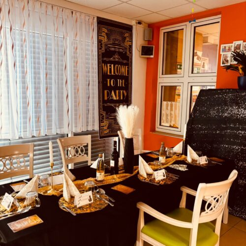 Festlich gedeckter Tisch mit schwarzen und goldenen Akzenten und Welcome to the Party Schild