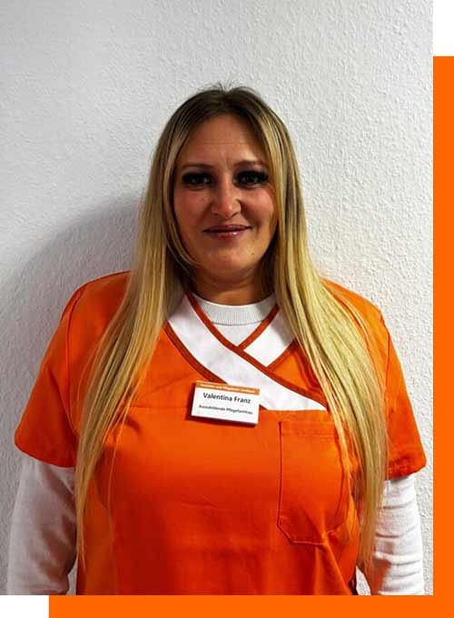 Laechelnde blonde Pflegefachkraft in orangefarbener Kleidung mit Namensschild